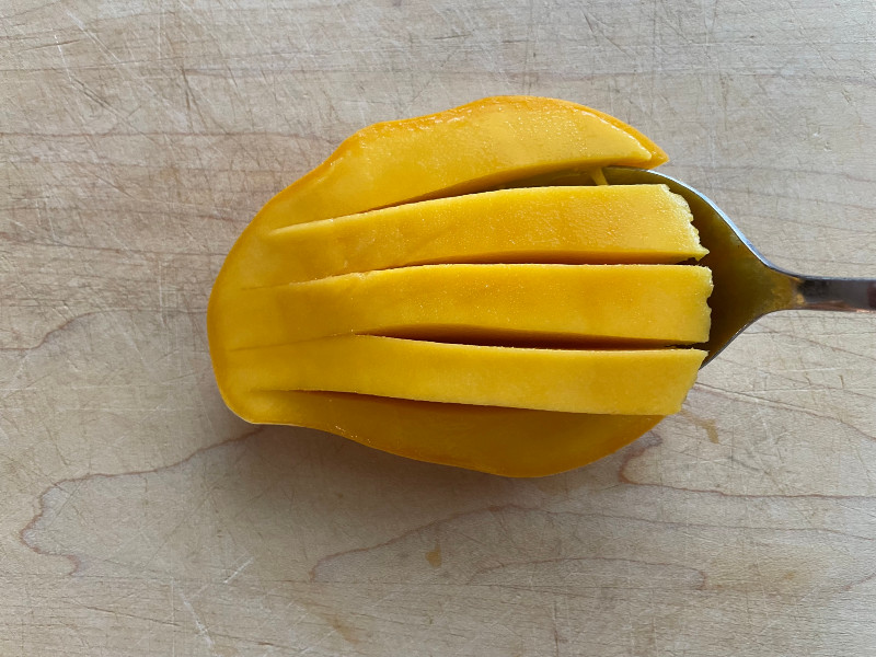 scooping out sliced mango