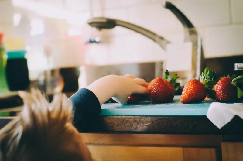 kid getting strawberry from counter