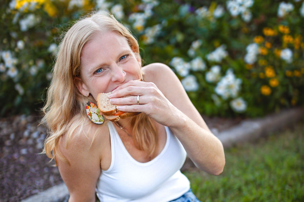 feeding you: woman biting sandwich